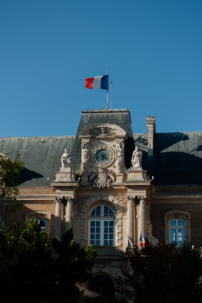 A picturesque view of a historic building in France with a French flag under a clear blue sky.