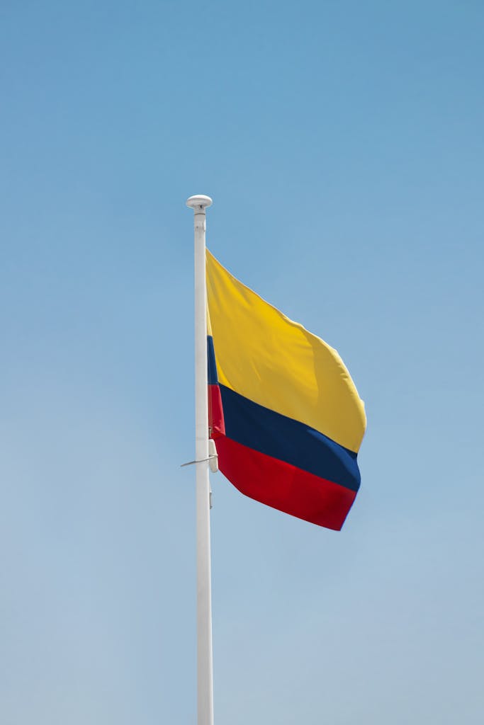 Bright Colombian flag waving on a sunny day with a clear blue sky backdrop.