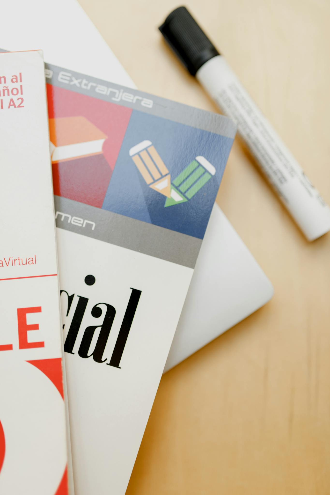 Close-up shot of Spanish language books and a marker on a wooden surface.
