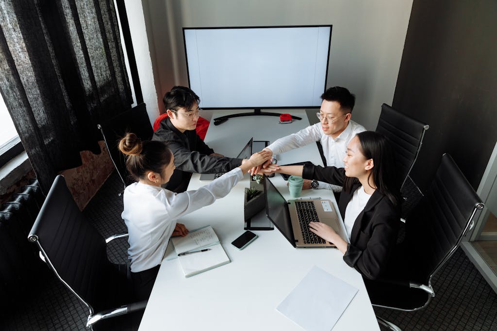 Asian business team collaborating and shaking hands during an office meeting.