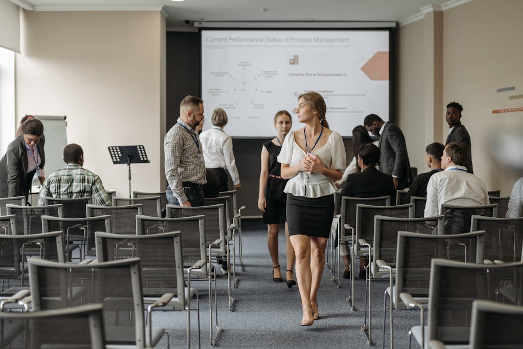 Professionals at a business conference engage before a presentation in a modern office.